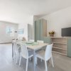 Sala da pranzo moderna con tavolo, sedie bianche e televisore.