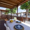 Veranda in legno con tavolo apparecchiato, vista su altre verande, alberi.
