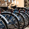 Biciclette blu allineate con parafanghi bianchi, edificio giallo sullo sfondo.