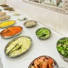 Buffet con insalate e verdure in ciotole metalliche.