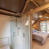 Camera mansardata in legno con letto e bagno con doccia.