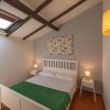 Camera da letto con finestra, letto bianco e travi in legno.