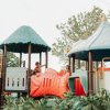 Bambini che giocano su una colorata struttura di un parco giochi all'aperto.