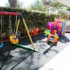 Parco giochi con altalene e scivolo colorato.