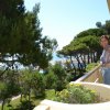 Donna sul balcone con vista su alberi e mare.
