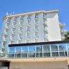 Edificio moderno bianco con balconi, circondato da palme, cielo blu sullo sfondo.