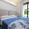 Camera d'albergo moderna con letto matrimoniale, copriletto blu e balcone con vista su un giardino.