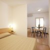 Interni di una stanza con letto matrimoniale, tavolo con sedie e finestra.