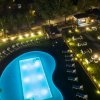 Piscina illuminata di sera con lettini e giardino.