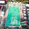 Vista dall'alto di una piscina con persone che nuotano e ombrelloni attorno.