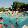 Persone nuotano e si divertono in una piscina all'aperto con scivolo.
