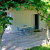 Terrazza esterna con tavolo, sedie blu e pergola verde, circondata da giardino.