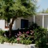 Una casa bianca con finestre, circondata da alberi e cespugli in fiore.