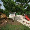 Un parco giochi con scivoli e aree gioco tra gli alberi.
