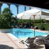 Una piscina con lettini e ombrelloni bianchi, circondata da palme e cespugli.