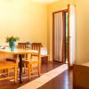Sala luminosa con tavolo in legno, sedie, portafiori e porta aperta.