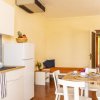 Cucina moderna con tavolo apparecchiato. Pareti chiare, frigorifero bianco e sedie bianche.