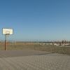 Campo da basket su una spiaggia con ombrelloni chiusi e mare all'orizzonte.