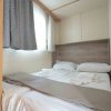 Camera con letto matrimoniale, lenzuola bianche, tende e una finestra luminosa.