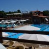 Una piscina con corsie e ombrelloni bianchi su un ponte, edificio in legno sullo sfondo.
