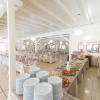 Un buffet con piatti pieni di cibo, vicino a tavoli apparecchiati in una sala da pranzo luminosa.