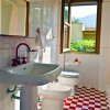 Un bagno con finestra, lavandino, bidet e WC. Piastrelle a scacchi rosse e bianche.