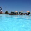 Piscina all'aperto con ombrelloni colorati sotto un cielo blu.