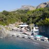 Spiaggia rocciosa con ombrelloni e lettini.