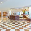 Una hall di hotel con pavimento a scacchi marrone e bianco, colonne di marmo e soffitto luminoso.