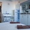 Interno angolo cottura con letto, tavolo bianco e accesso a un bagno.