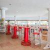 Un'area ristoro con tavolini rossi, sedie e distributori automatici.