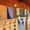 Veranda in legno con tavolo e sedie bianche, porta e finestre.