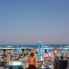 Spiaggia affollata con ombrelloni blu e persone che prendono il sole.