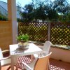 Terrazza con tavolo e sedie bianchi, pianta in vaso, luce solare.
