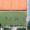 Campo sportivo con calciatori in allenamento, visto dall'alto. Campi adiacenti.