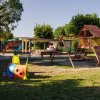 Parco giochi con strutture di legno e un bruco colorato.