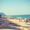 Spiaggia affollata con ombrelloni colorati.
