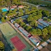Vista aerea di un complesso con campi da tennis, piscine e edifici immersi nel verde.
