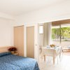 Appartamento con letto matrimoniale, tavolo da pranzo e vista su balcone verde.
